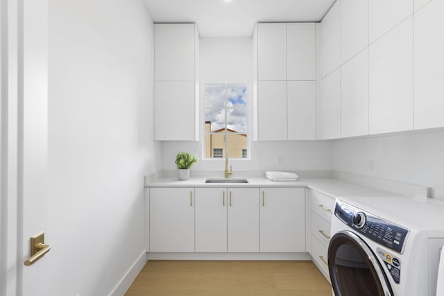 clothes washing area featuring sink, cabinets, light hardwood / wood-style flooring, and washer / dryer