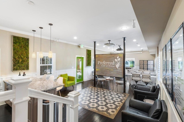 interior space with dark wood-type flooring, a kitchen breakfast bar, pendant lighting, and ornamental molding