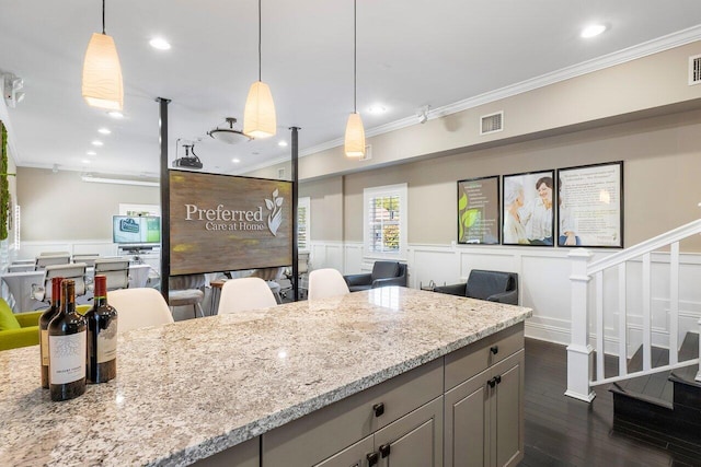 kitchen with pendant lighting, dark hardwood / wood-style floors, light stone countertops, and ornamental molding