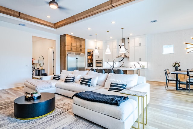 living room with light hardwood / wood-style flooring, ceiling fan, and sink