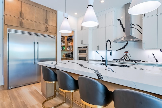 kitchen featuring pendant lighting, white cabinets, light hardwood / wood-style floors, and stainless steel appliances