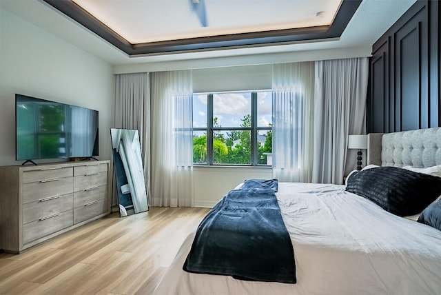 bedroom featuring light wood-type flooring and a raised ceiling