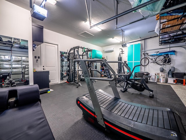 workout area featuring a wall unit AC and a textured ceiling