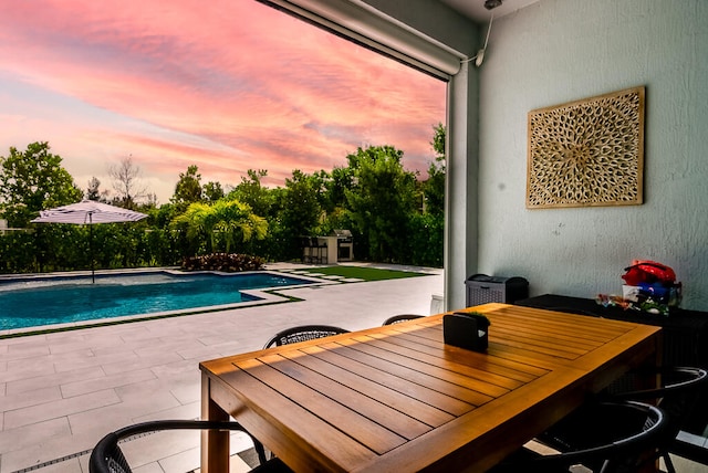 pool at dusk featuring a patio