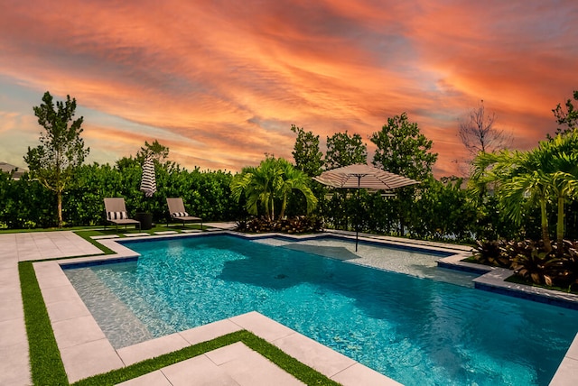 pool at dusk with a patio area