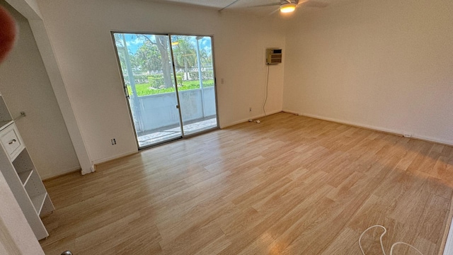 spare room with ceiling fan, a wall unit AC, and light hardwood / wood-style flooring