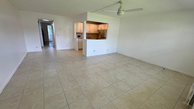 unfurnished living room with a textured ceiling, ceiling fan, and light tile patterned floors