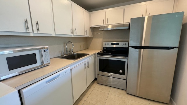 kitchen with appliances with stainless steel finishes, white cabinetry, light tile patterned floors, and sink