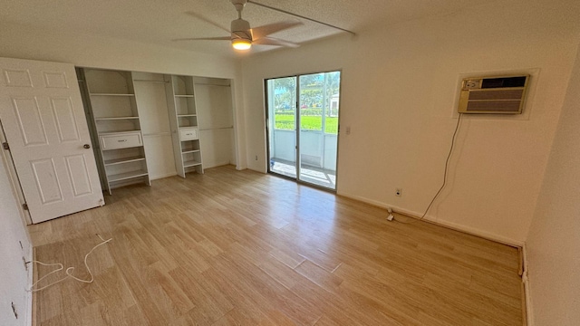 unfurnished bedroom with light hardwood / wood-style floors, access to outside, ceiling fan, an AC wall unit, and a textured ceiling