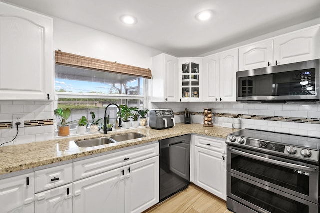 kitchen featuring decorative backsplash, white cabinetry, appliances with stainless steel finishes, and sink