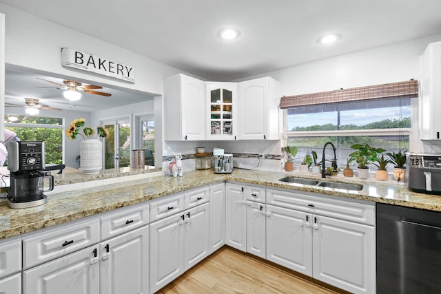 kitchen featuring white cabinets, backsplash, sink, and stainless steel dishwasher