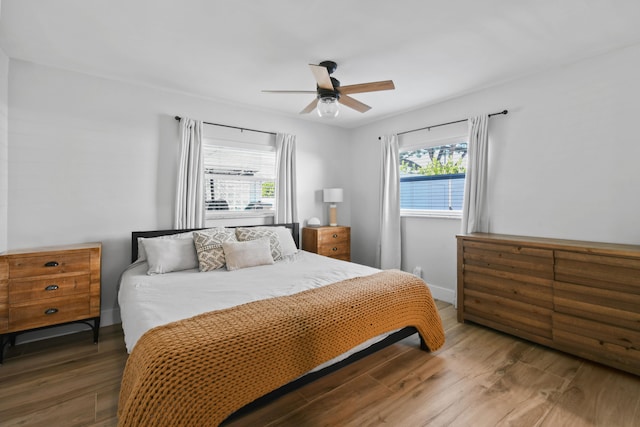 bedroom featuring multiple windows, hardwood / wood-style floors, and ceiling fan