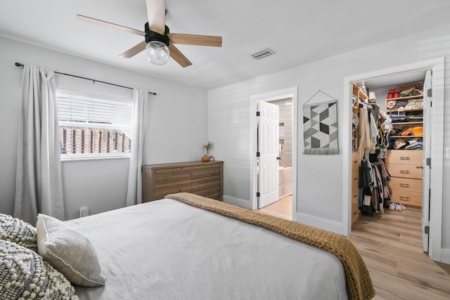 bedroom with ceiling fan, connected bathroom, a closet, a spacious closet, and light wood-type flooring