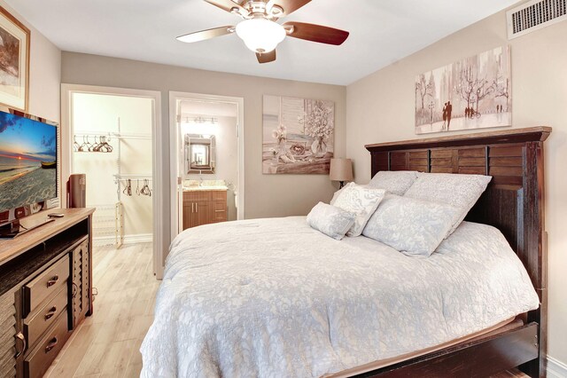 bedroom with light hardwood / wood-style flooring, ensuite bath, and ceiling fan