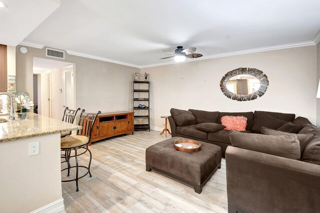 living room with ornamental molding, light hardwood / wood-style flooring, sink, and ceiling fan