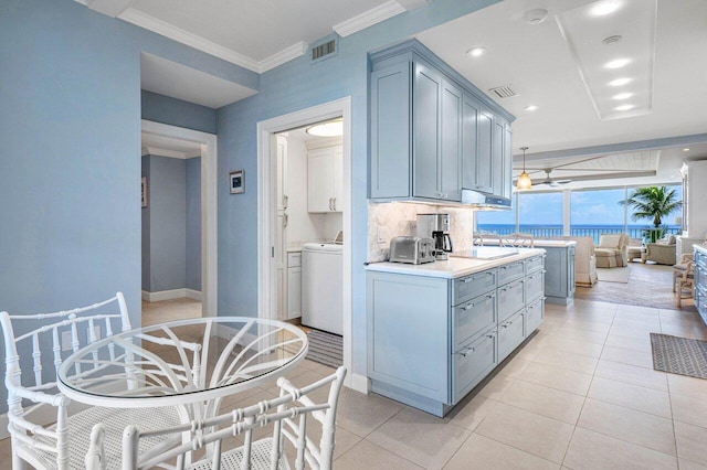 kitchen featuring crown molding, washer / dryer, light tile patterned floors, and decorative backsplash