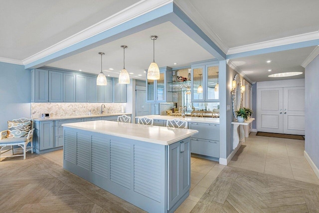 kitchen with a center island, blue cabinetry, decorative light fixtures, sink, and ornamental molding