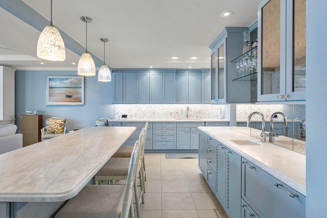 kitchen featuring backsplash, light tile patterned floors, sink, a kitchen breakfast bar, and pendant lighting