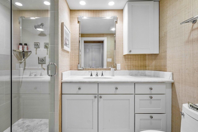 bathroom featuring a shower with shower door, toilet, and vanity