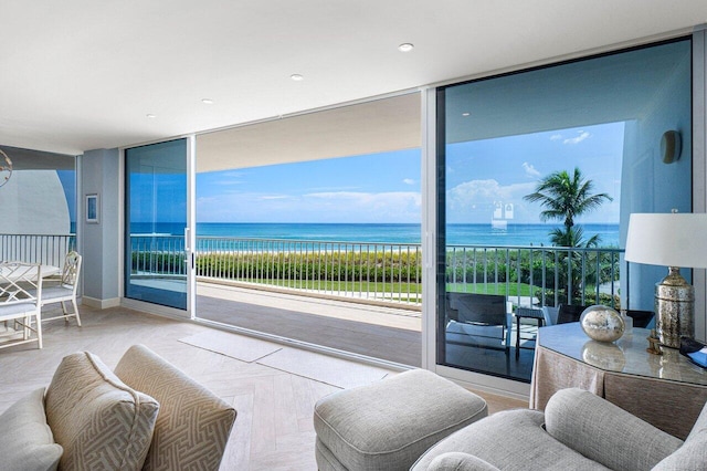 living room with a wall of windows, a water view, and light parquet flooring