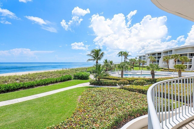 exterior space with a view of the beach, a water view, a yard, and a pool