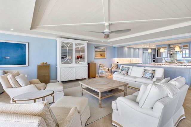 living room featuring ornamental molding, light hardwood / wood-style flooring, a tray ceiling, and ceiling fan