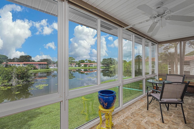 unfurnished sunroom featuring ceiling fan and a water view