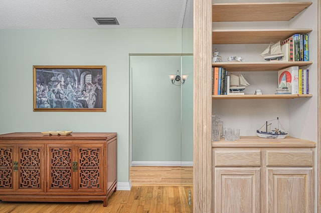 hallway with light wood-type flooring and a textured ceiling