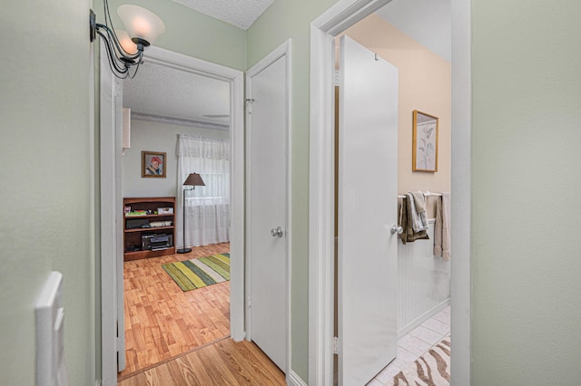 hall featuring light hardwood / wood-style floors and a textured ceiling