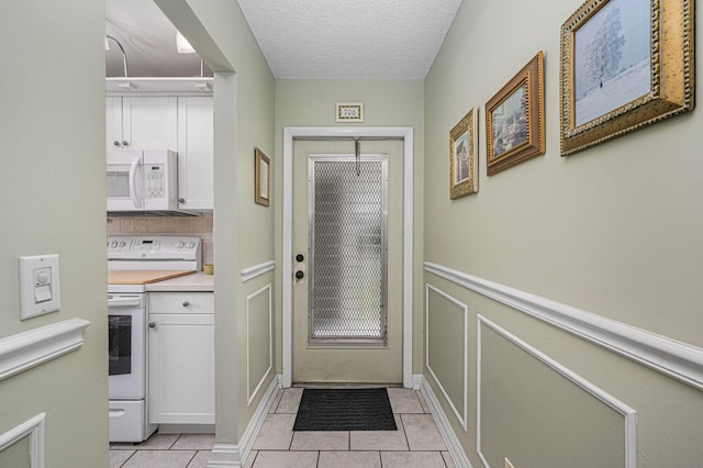 doorway with a textured ceiling and light tile patterned floors