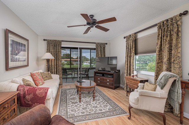 living room featuring ceiling fan, plenty of natural light, light hardwood / wood-style floors, and a textured ceiling