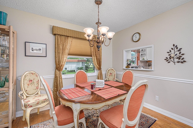 dining room with a chandelier, light hardwood / wood-style floors, and a textured ceiling