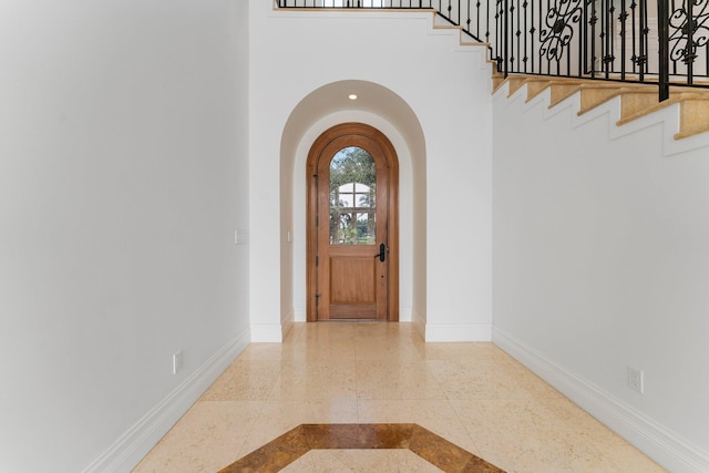 13058 Flamingo Ter, Palm Beach Gardens, FL 33410 - entrance foyer with inlaid floor details, baseboards, arched walkways, a high ceiling, and stairway