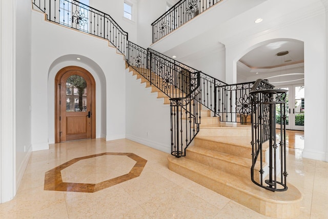 foyer entrance with a raised ceiling, ornamental molding, and a towering ceiling