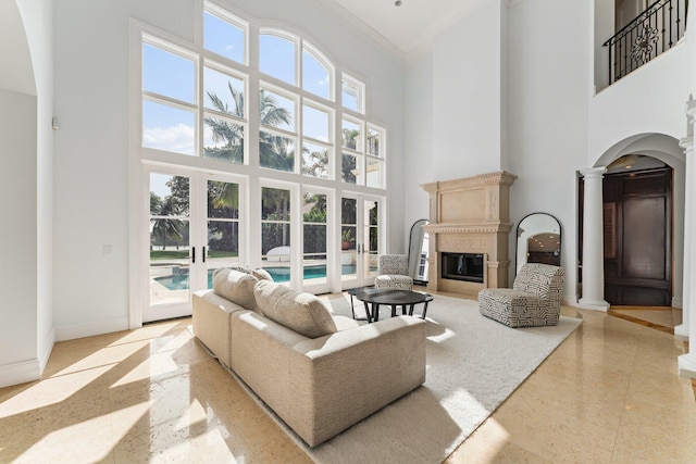 13058 Flamingo Ter, Palm Beach Gardens, FL 33410 - living area featuring a high ceiling, a glass covered fireplace, ornamental molding, decorative columns, and arched walkways
