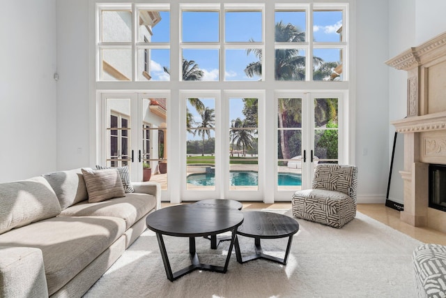 living room with a high ceiling, a healthy amount of sunlight, a high end fireplace, and french doors