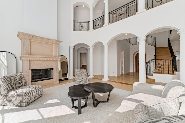 living room with a towering ceiling, a premium fireplace, and ornate columns