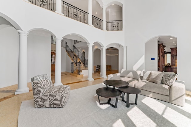 living room featuring a high ceiling, decorative columns, and crown molding