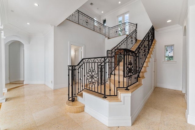 stairs with crown molding and a high ceiling