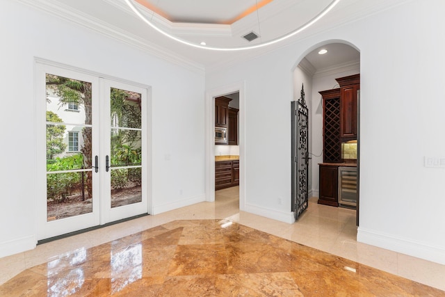 unfurnished bedroom with french doors, a raised ceiling, beverage cooler, connected bathroom, and ornamental molding