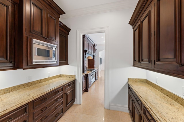 13058 Flamingo Ter, Palm Beach Gardens, FL 33410 - kitchen featuring stainless steel microwave, dark brown cabinets, ornamental molding, light stone countertops, and baseboards