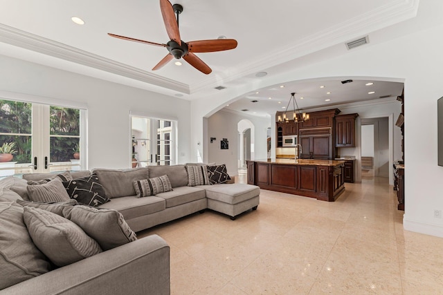 living room with ceiling fan with notable chandelier, crown molding, and sink