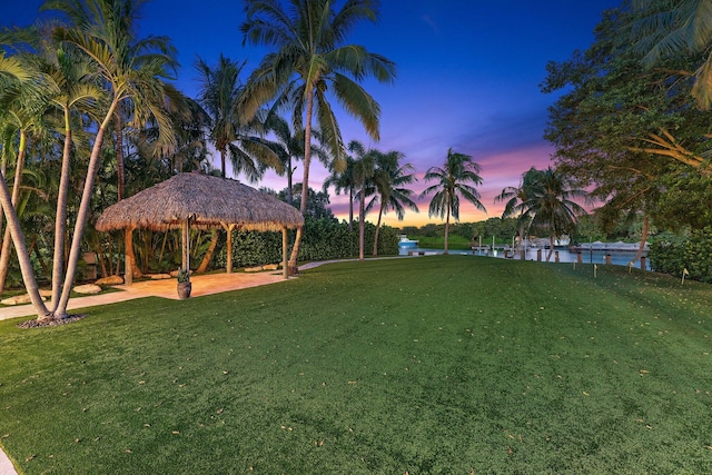 yard at dusk featuring a water view and a gazebo