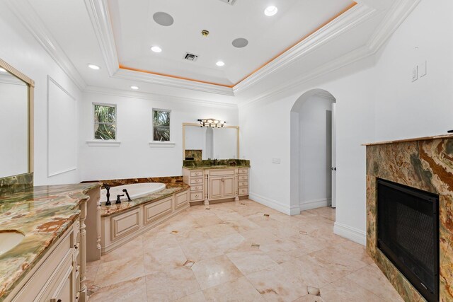 13058 Flamingo Ter, Palm Beach Gardens, FL 33410 - full bathroom with a tiled fireplace, ornamental molding, two vanities, a bath, and a raised ceiling