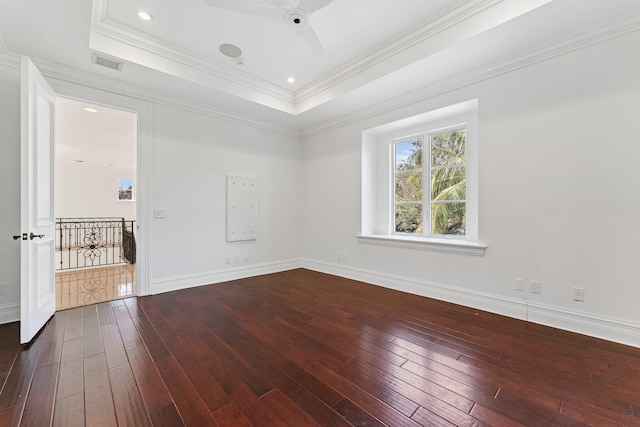 unfurnished room featuring a tray ceiling, ceiling fan, dark hardwood / wood-style floors, and crown molding