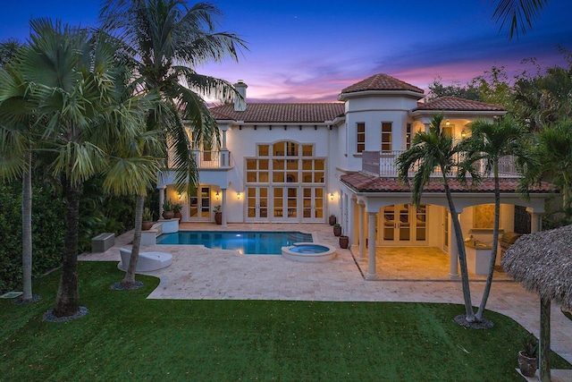 pool at dusk featuring french doors, a lawn, and a patio