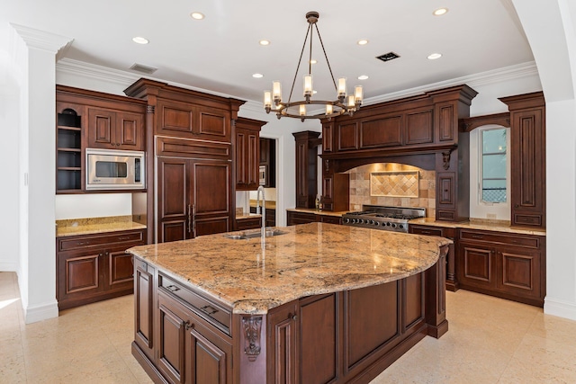 kitchen featuring a chandelier, sink, an island with sink, built in appliances, and ornamental molding