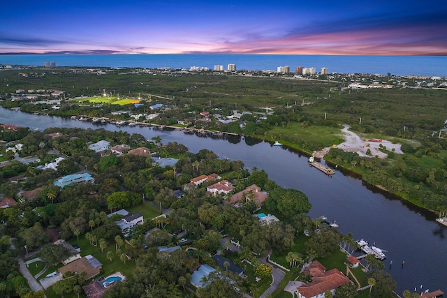 aerial view at dusk featuring a water view