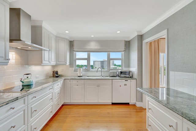 kitchen featuring white dishwasher, wall chimney exhaust hood, and white cabinetry