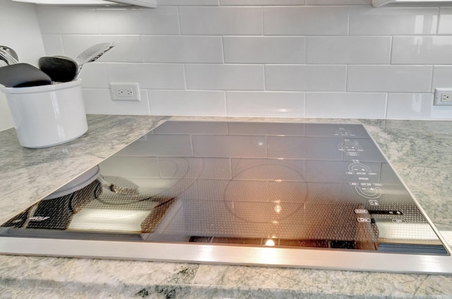 interior details with decorative backsplash and stainless steel cooktop